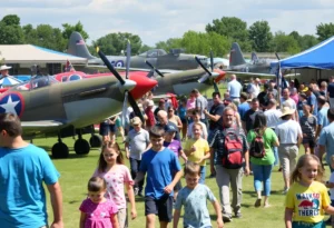 Families enjoying the Aviation Discovery Fest at Dallas Executive Airport with vintage aircraft in the background.